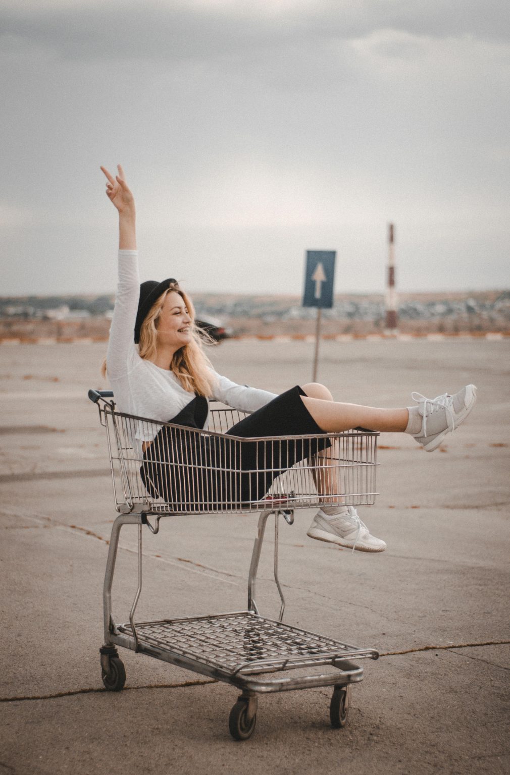 Carefree woman enjoying a fun moment in a shopping cart outdoors.